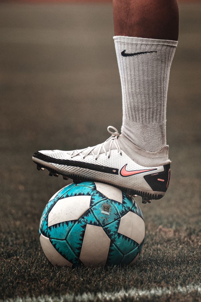 A person in sportswear balancing a blue soccer ball on grassy field.